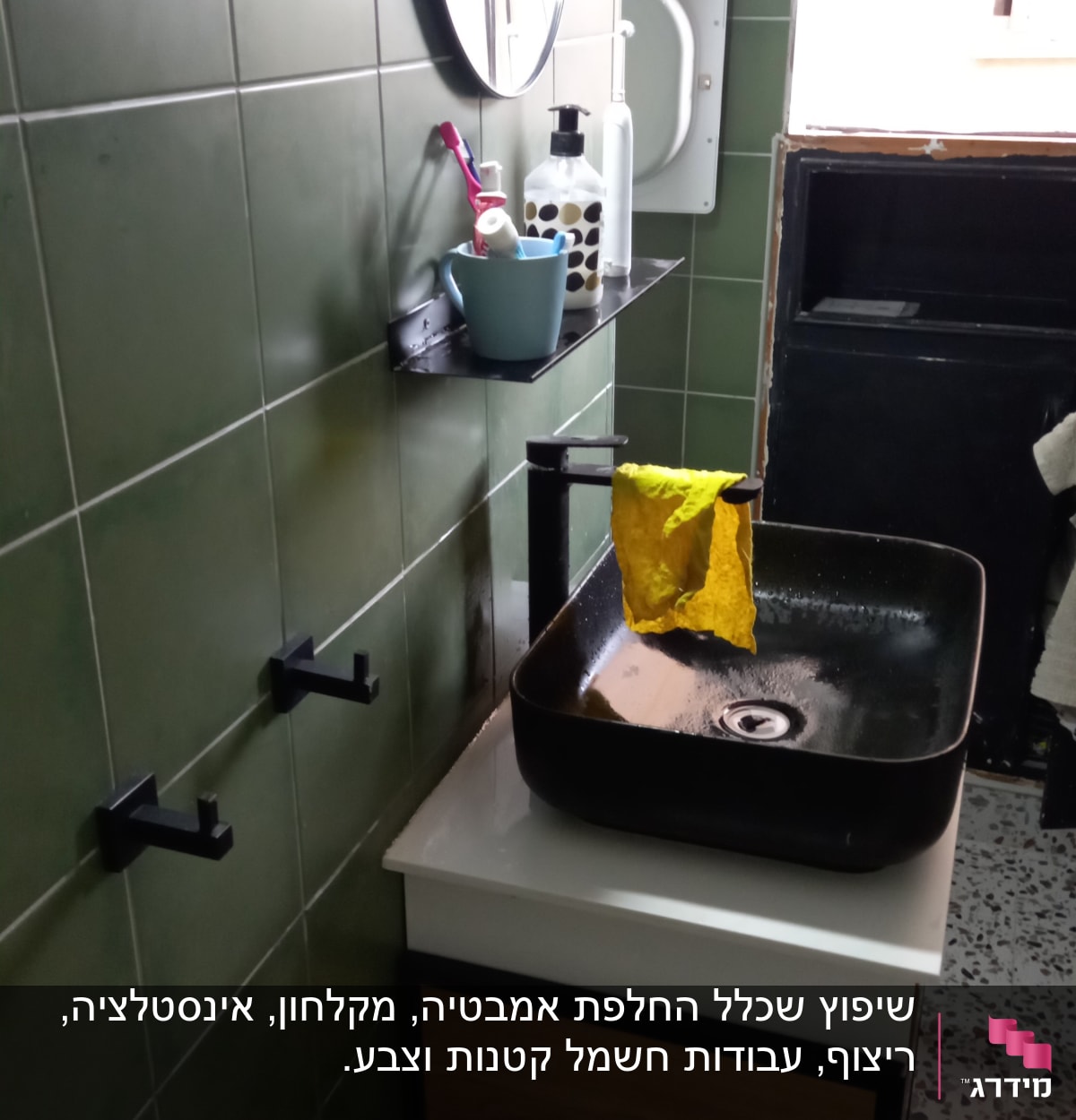 כיור שחור עם ברז ומטלית צהובה, מדף עם מוצרים